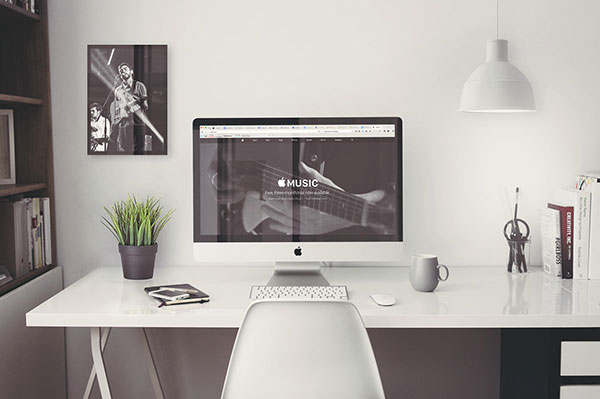 The mockup of an iMac Retina 5k on a desk next to a plant FREE PSD