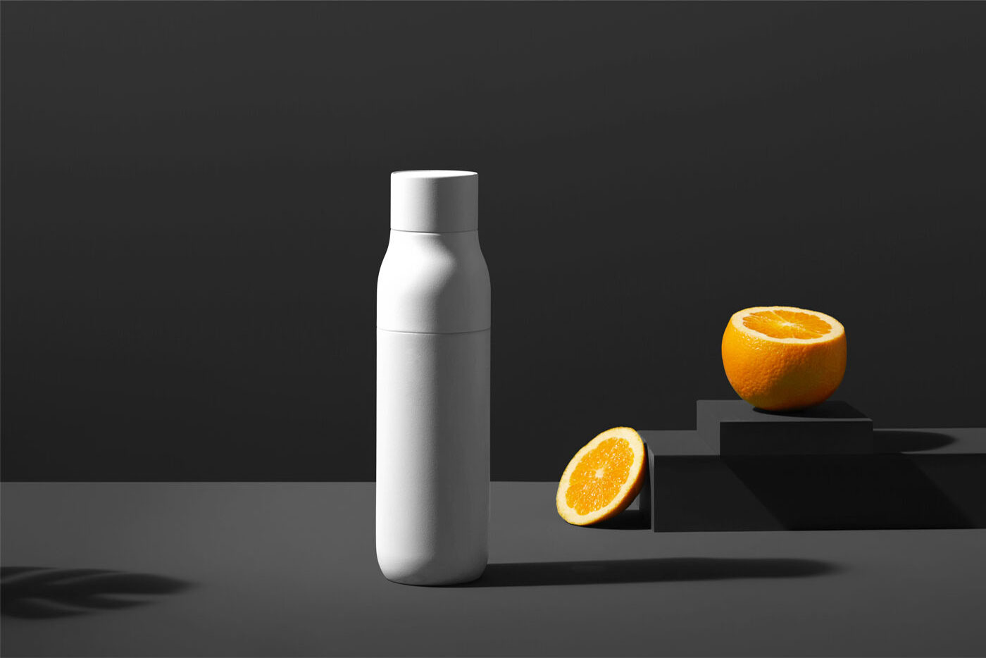 Juice Bottle Mockup in a Solid Color Background next to Sliced Orange FREE PSD
