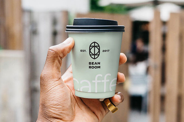 Mockup a Man's Hand Holding a Cup with Blur City Background FREE PSD