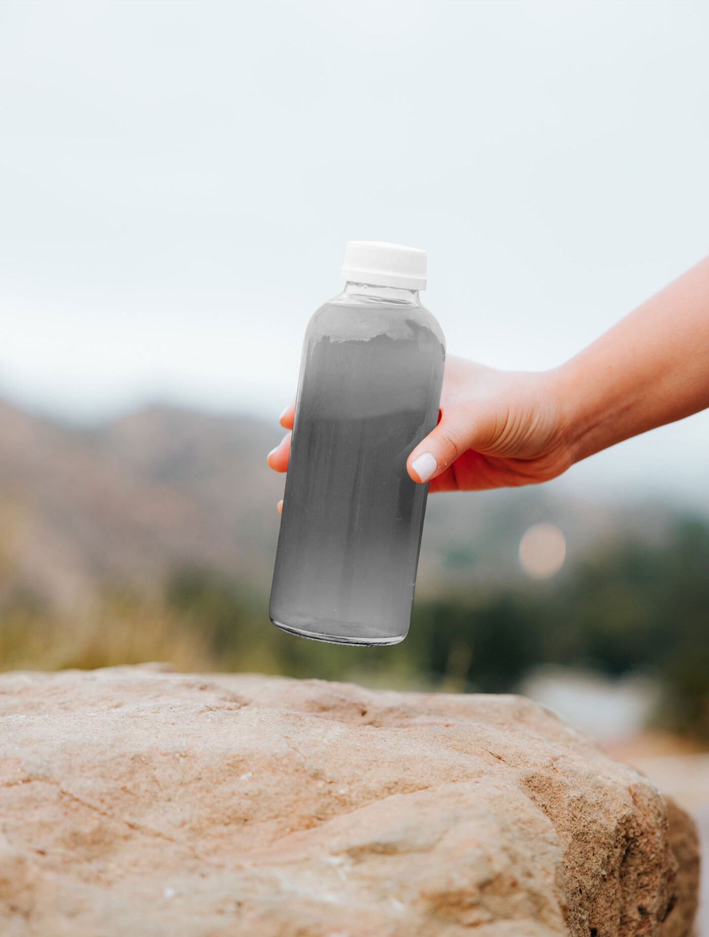 Mockup of a Transparent Bottle Held by Hand FREE PSD