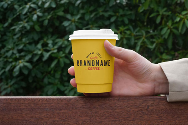 Hand Holding Paper Coffee Cup on Bench Mockup FREE PSD
