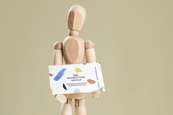 Business Card Held in Hands of a Wooden Manikin Mockup FREE PSD