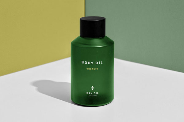 Front View of Body Oil Bottle at the Corner of Two Walls Mockup FREE PSD