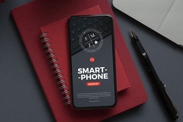 Smartphone Mockup Laid on Notebook in Top View FREE PSD
