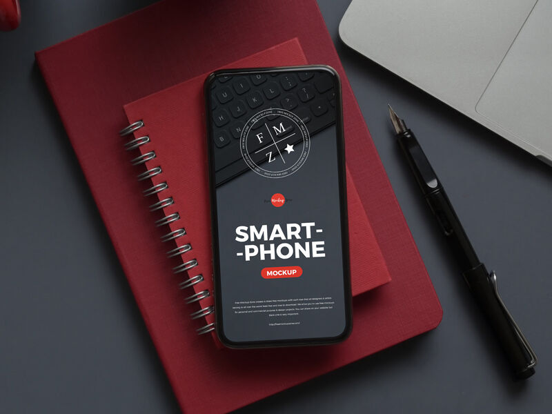 Smartphone Mockup Laid on Notebook in Top View FREE PSD