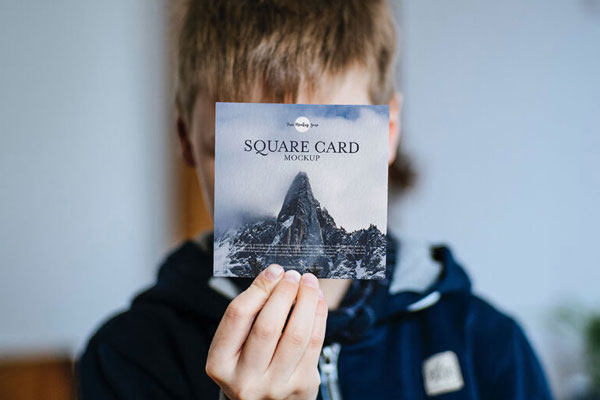 Front View of a Little Boy Showing a Square Card Mockup FREE PSD