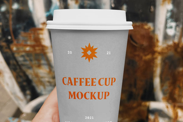 Hand Holding a Coffee Cup on a Street Mockup FREE PSD