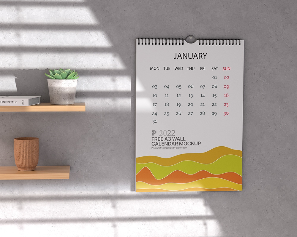 A3 Calendar Hung on the Wall Mockup Featuring Wooden Shelves and Plant