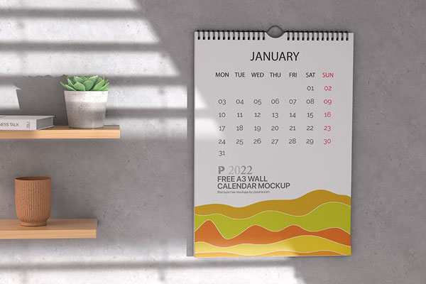 A3 Calendar Hung on the Wall Mockup Featuring Wooden Shelves and Plant Pots FREE PSD