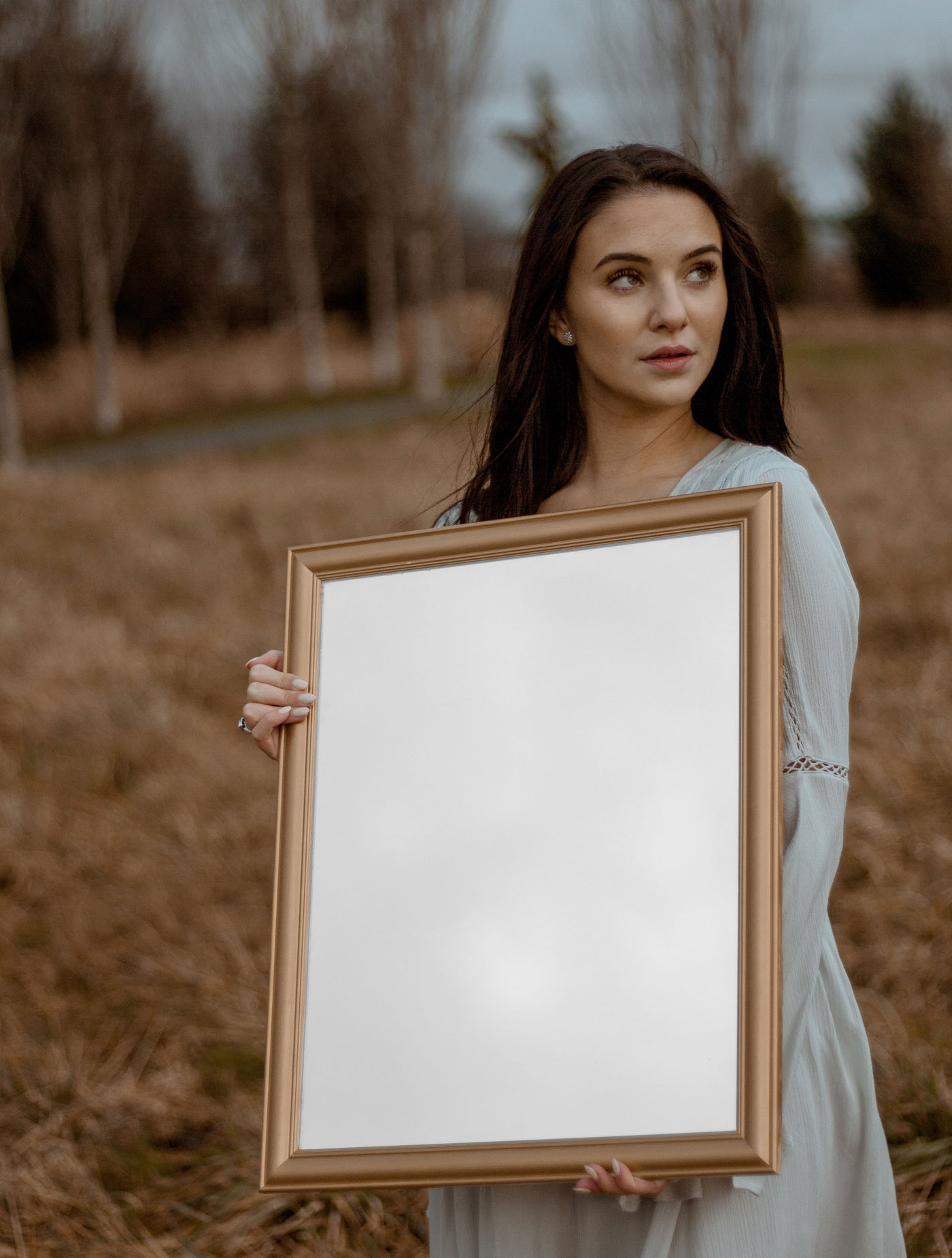 Woman Holding a Front View of Vertical Poster Mockup in Nature FREE PSD