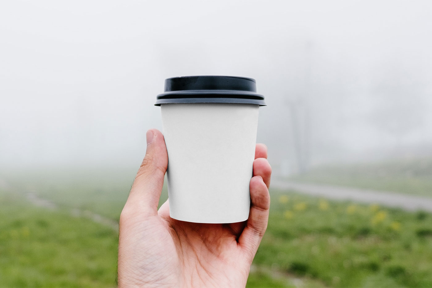 Front View of Hand Holding Coffee Cup Mockup in Park FREE PSD