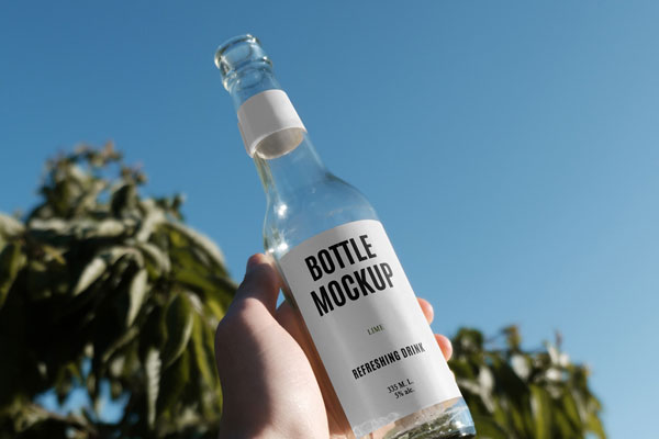 Handholding Glass Bottle Mockup in Nature FREE PSD
