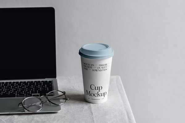 Free Front Sight of Paper Coffee Cup Mockup with MacBook PSD Template