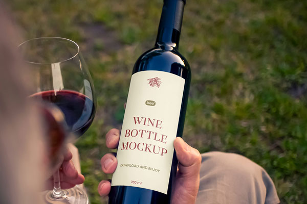 Free Wine Bottle in Hand Mockup PSD Template