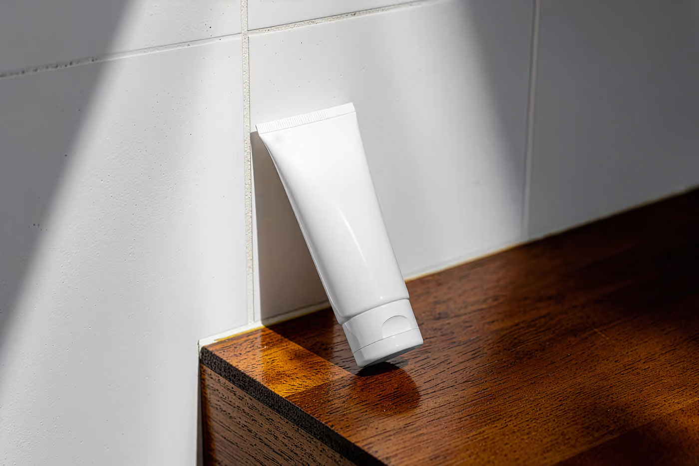 Free Cosmetic Tube Leans Against Wall Mockup PSD Template