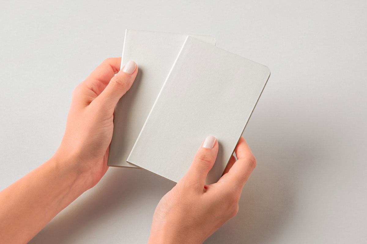 Free Hands Holding Pocket Classic Notebooks Mockup PSD Template