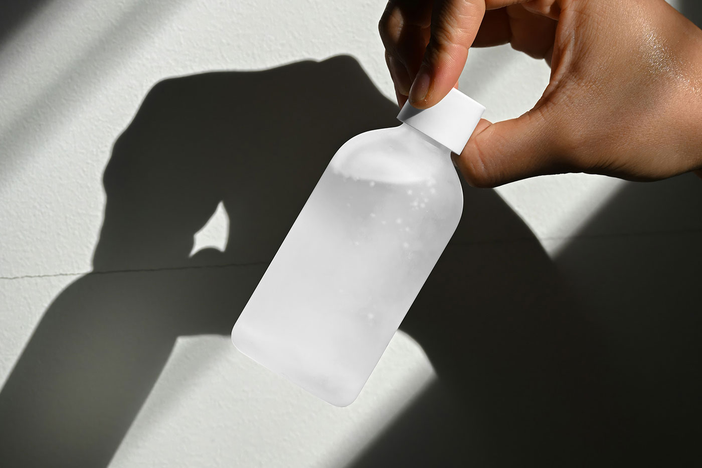 Free Cosmetic Glass Bottle in Hand Mockup PSD Template