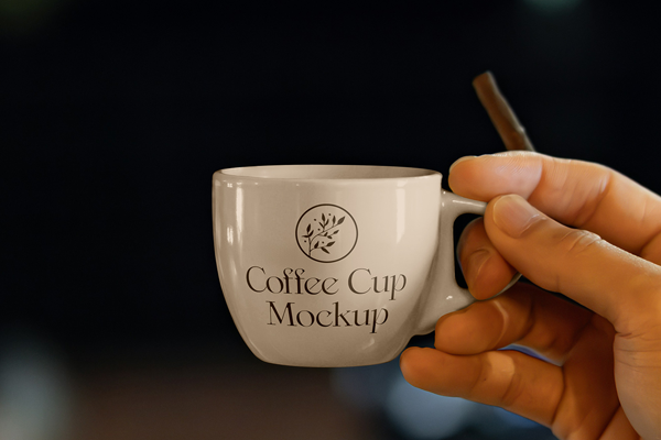 Free Small Porcelain Cup in Hand Mockup PSD Template